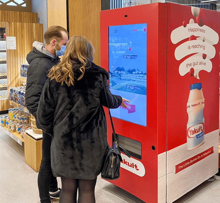 Two customers using a yakult machine